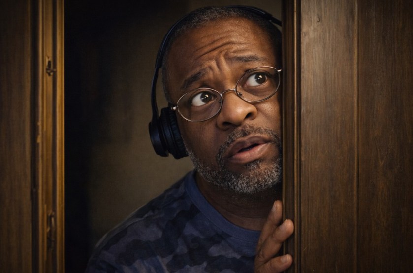 Illustrated image of a Black man with headphones, hiding from his boss.